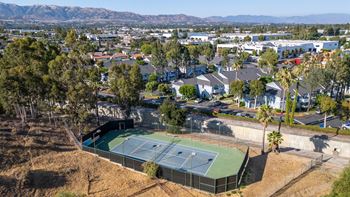 A tennis court is surrounded by houses and trees.